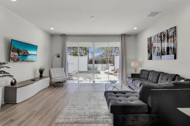 living room with a textured ceiling and light hardwood / wood-style flooring