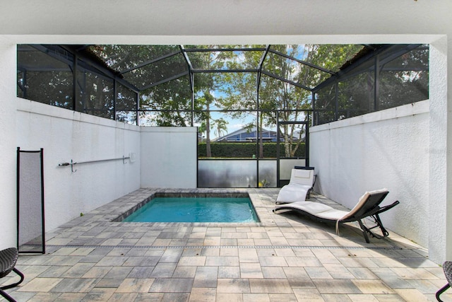 view of swimming pool with a patio, glass enclosure, and a hot tub