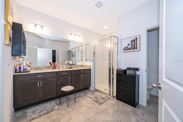 bathroom featuring toilet, a shower with shower door, and vanity