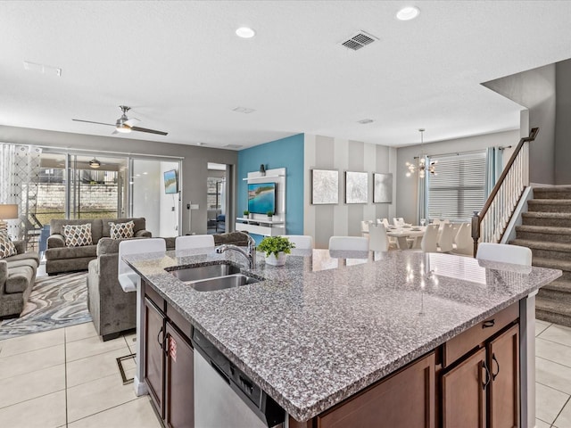 kitchen with dishwasher, a kitchen island with sink, light tile patterned floors, sink, and ceiling fan with notable chandelier