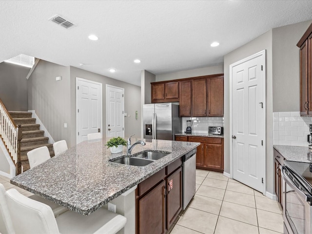 kitchen featuring appliances with stainless steel finishes, a kitchen breakfast bar, an island with sink, and sink