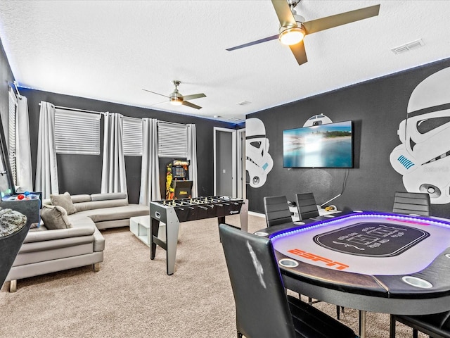 recreation room featuring a textured ceiling, ceiling fan, and carpet