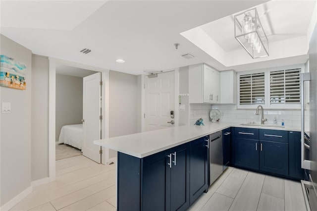 kitchen with sink, kitchen peninsula, white cabinets, and blue cabinets