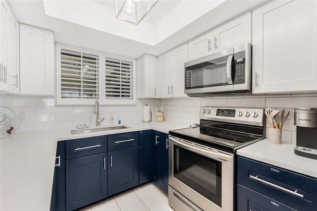 kitchen featuring blue cabinets, white cabinetry, appliances with stainless steel finishes, and sink