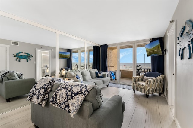 living room with expansive windows and light hardwood / wood-style flooring