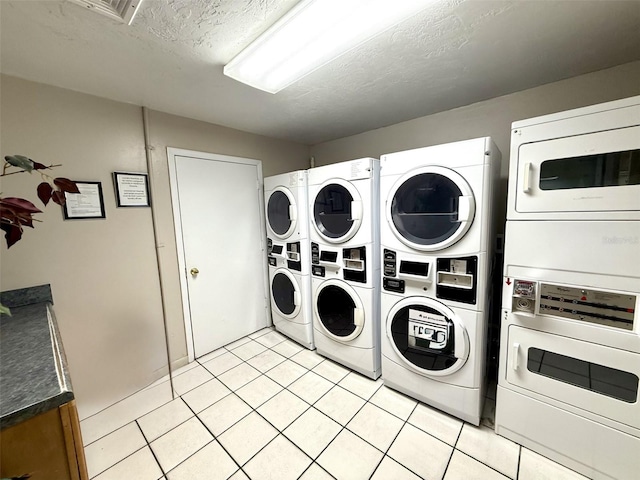 clothes washing area featuring light tile patterned flooring, stacked washer / drying machine, washing machine and dryer, and a textured ceiling