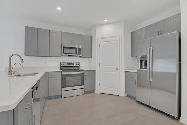 kitchen with appliances with stainless steel finishes, gray cabinets, and sink