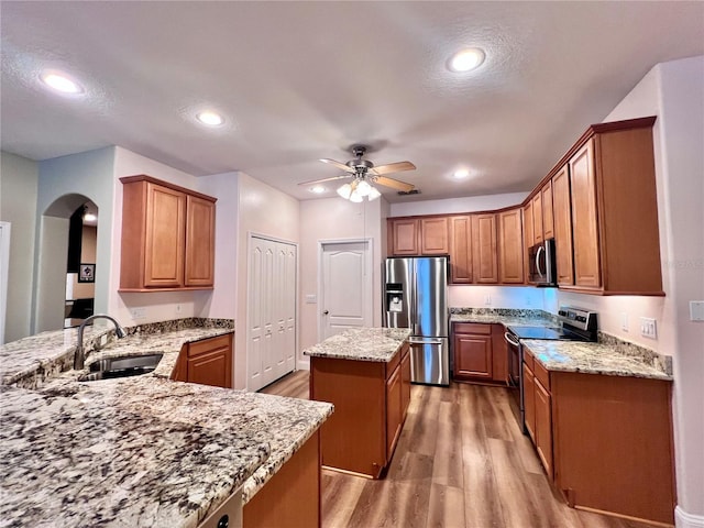 kitchen with hardwood / wood-style flooring, kitchen peninsula, stainless steel appliances, a center island, and sink