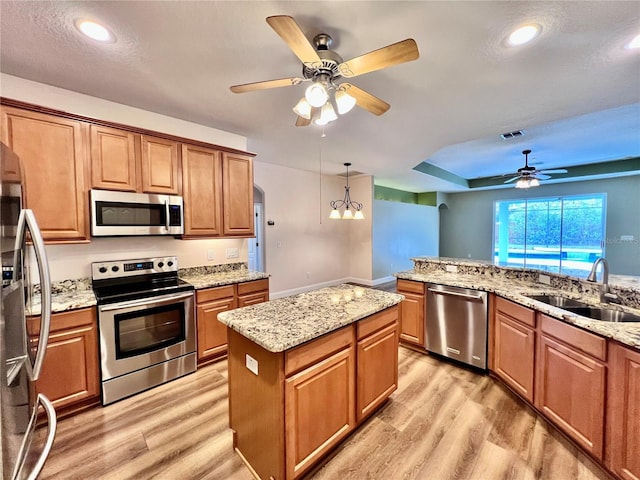 kitchen featuring stainless steel appliances, light hardwood / wood-style flooring, a center island, and sink