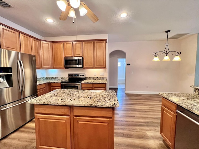 kitchen featuring stainless steel appliances, light hardwood / wood-style floors, hanging light fixtures, and a kitchen island