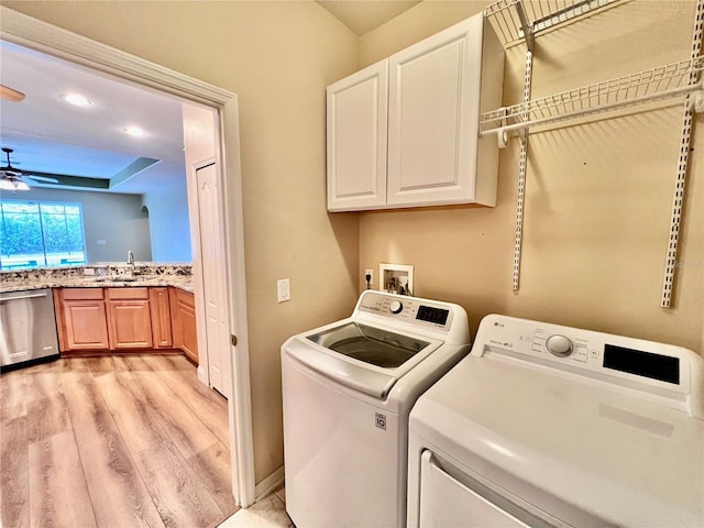 laundry room with ceiling fan, sink, washing machine and clothes dryer, light wood-type flooring, and cabinets