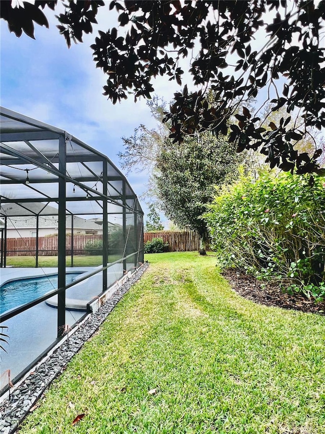 view of yard featuring a fenced in pool and glass enclosure