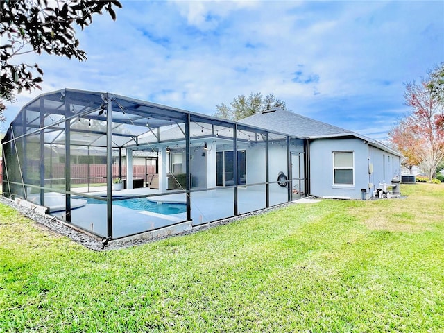 rear view of house with glass enclosure, a patio area, and a yard