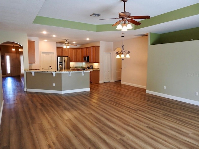 kitchen with a kitchen bar, dark hardwood / wood-style flooring, stainless steel appliances, sink, and light stone counters