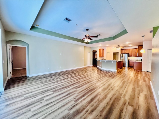 unfurnished living room with a raised ceiling and light hardwood / wood-style floors