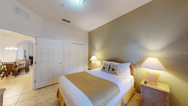 tiled bedroom with an inviting chandelier and a closet