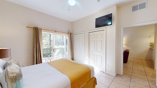 tiled bedroom with ceiling fan and multiple closets