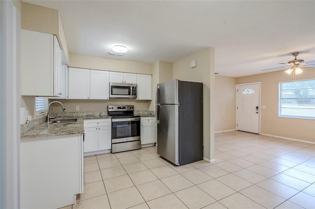 kitchen featuring white cabinetry, sink, light tile patterned floors, light stone counters, and stainless steel appliances