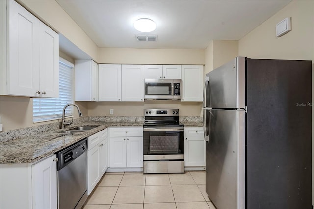 kitchen featuring sink, stainless steel appliances, light stone countertops, white cabinets, and light tile patterned flooring