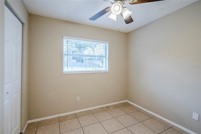 spare room with light tile patterned floors, a textured ceiling, and ceiling fan