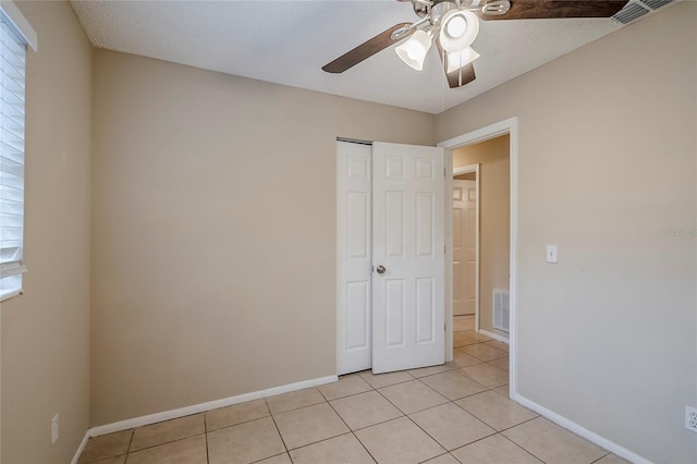 unfurnished bedroom featuring multiple windows, a closet, ceiling fan, and light tile patterned flooring