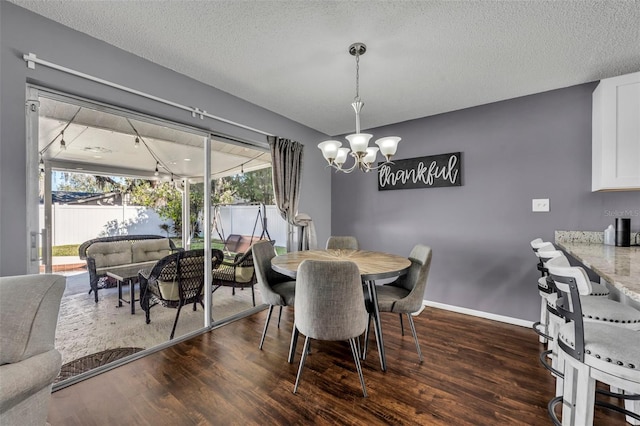 dining space with a chandelier, a textured ceiling, and dark wood-type flooring