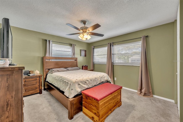 bedroom featuring light carpet, a textured ceiling, and ceiling fan