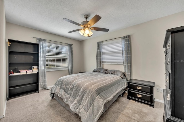 bedroom featuring ceiling fan, light colored carpet, and a textured ceiling