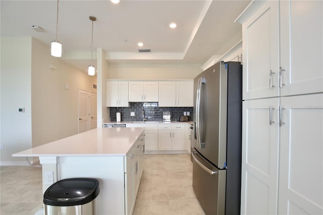 kitchen with stainless steel refrigerator, a center island, white cabinets, decorative light fixtures, and sink