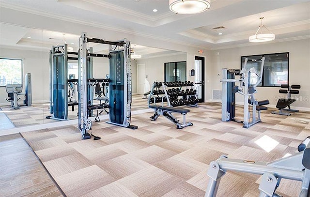 workout area with a raised ceiling and ornamental molding