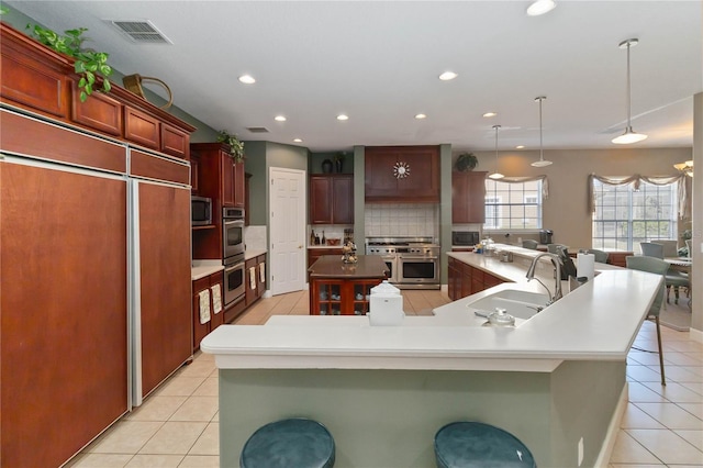 kitchen with decorative light fixtures, a large island, backsplash, appliances with stainless steel finishes, and sink