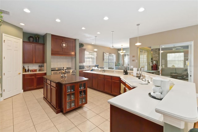 kitchen featuring a large island, hanging light fixtures, sink, light tile patterned flooring, and ceiling fan with notable chandelier