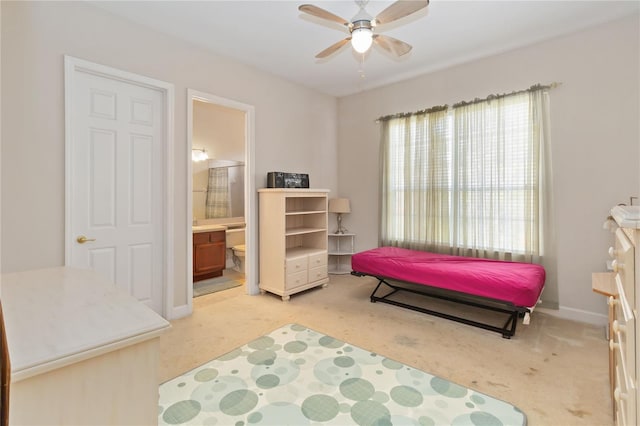 carpeted bedroom with ensuite bathroom and ceiling fan