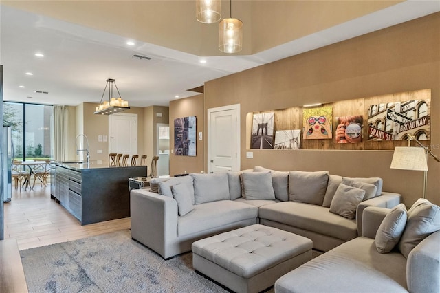 living room with sink, light hardwood / wood-style floors, and an inviting chandelier