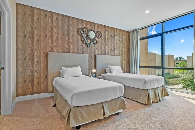 carpeted bedroom featuring floor to ceiling windows and wood walls