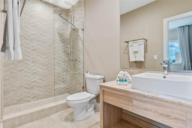 bathroom with toilet, vanity, tile patterned floors, and tiled shower