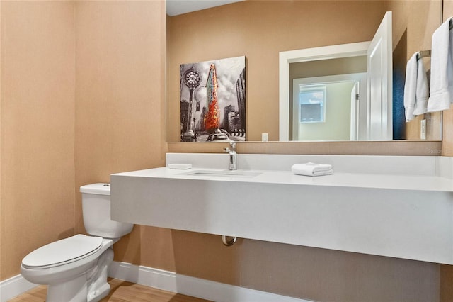 bathroom with sink, toilet, and hardwood / wood-style floors