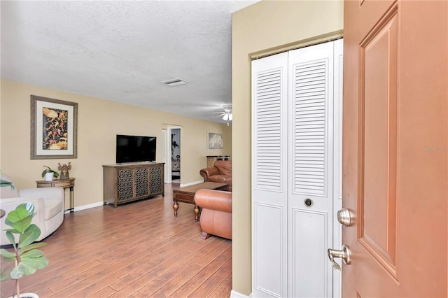 living room with hardwood / wood-style flooring, a textured ceiling, and ceiling fan