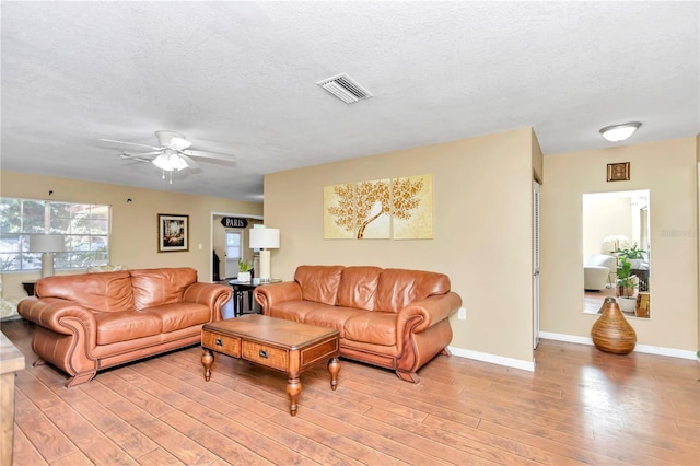 living room featuring a textured ceiling, ceiling fan, and light wood-type flooring