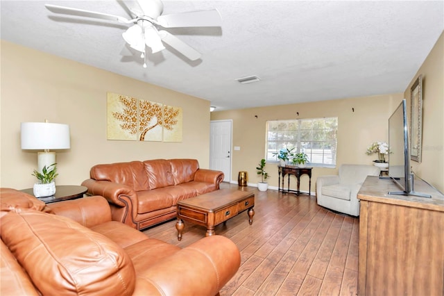 living room with hardwood / wood-style flooring, a textured ceiling, and ceiling fan