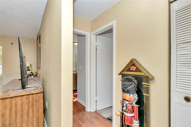 hallway featuring a textured ceiling and light hardwood / wood-style flooring