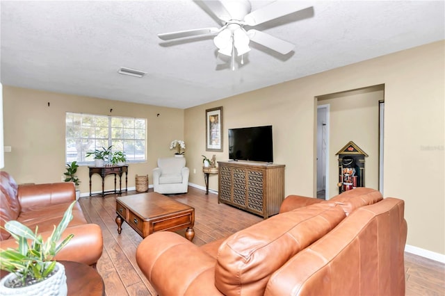 living room with ceiling fan, light wood-type flooring, and a textured ceiling