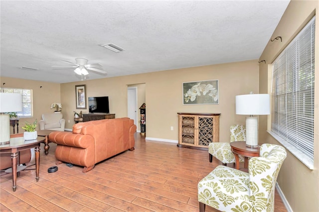 living room featuring a textured ceiling, ceiling fan, and light hardwood / wood-style flooring