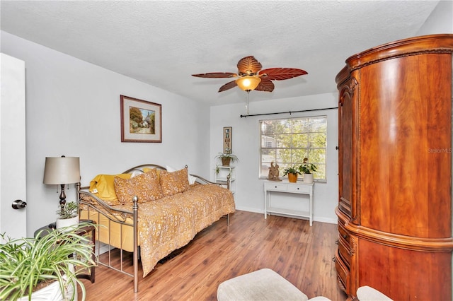 living room with a textured ceiling, ceiling fan, and wood-type flooring