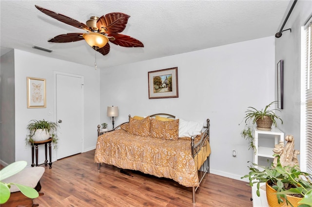 bedroom with ceiling fan, a textured ceiling, and wood-type flooring