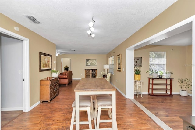 dining room featuring a textured ceiling, ceiling fan, and dark hardwood / wood-style flooring