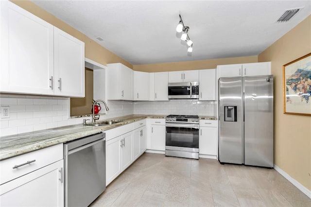 kitchen featuring light stone counters, stainless steel appliances, backsplash, white cabinetry, and sink