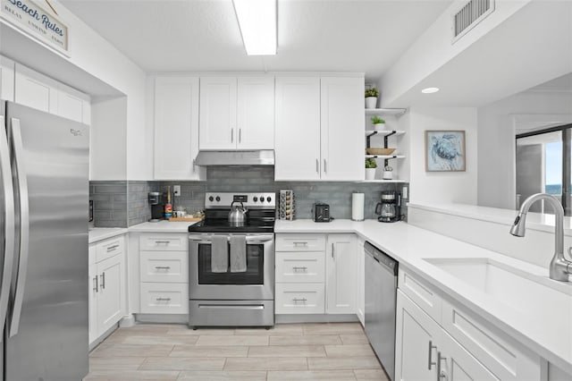 kitchen featuring white cabinets, appliances with stainless steel finishes, backsplash, and sink