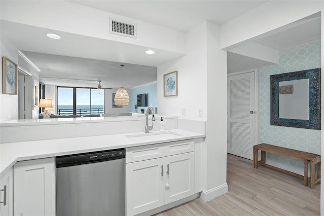 kitchen featuring stainless steel dishwasher, light hardwood / wood-style flooring, decorative light fixtures, white cabinets, and sink