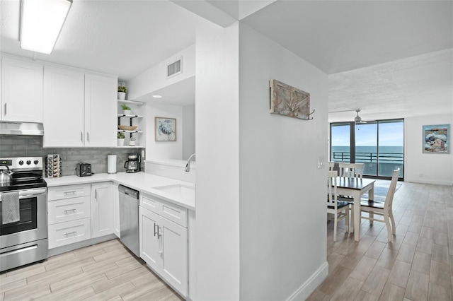 kitchen featuring sink, stainless steel appliances, a water view, and white cabinetry